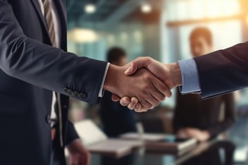 Two businesspeople in suits shaking hands, representing a co-managed IT services partnership between an in-house team and an outside provider